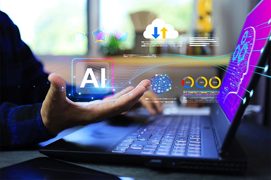 A close-up of a person’s hand held over a laptop keyboard, with futuristic digital graphics floating above it. A prominent "AI" icon is centered, surrounded by colorful waves, a cloud icon, and circular data charts. The laptop screen shows a glowing silhouette of a human head filled with gears.
